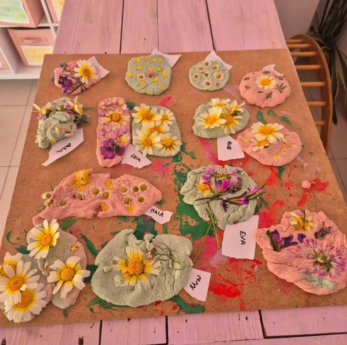 Piezas de arcilla con flores prensadas secándose sobre la mesa