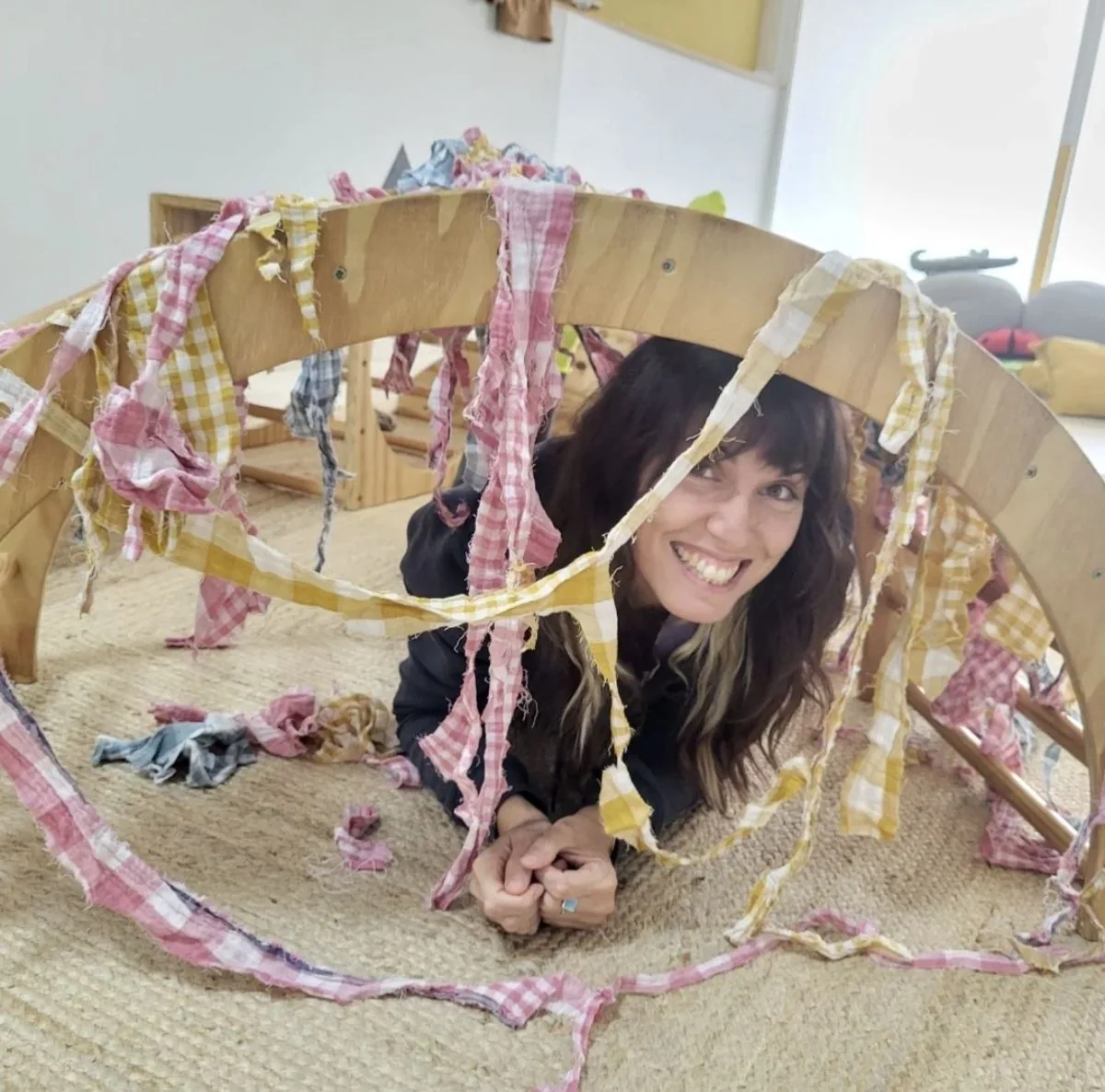 Una acompañante asomada por un túnel de telas en la sala de juego